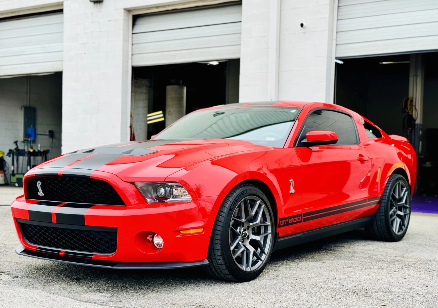 Red 2007 Shelby GT500 Mustang with black stripes parked outside STL Auto Defenders after its custom PPF project