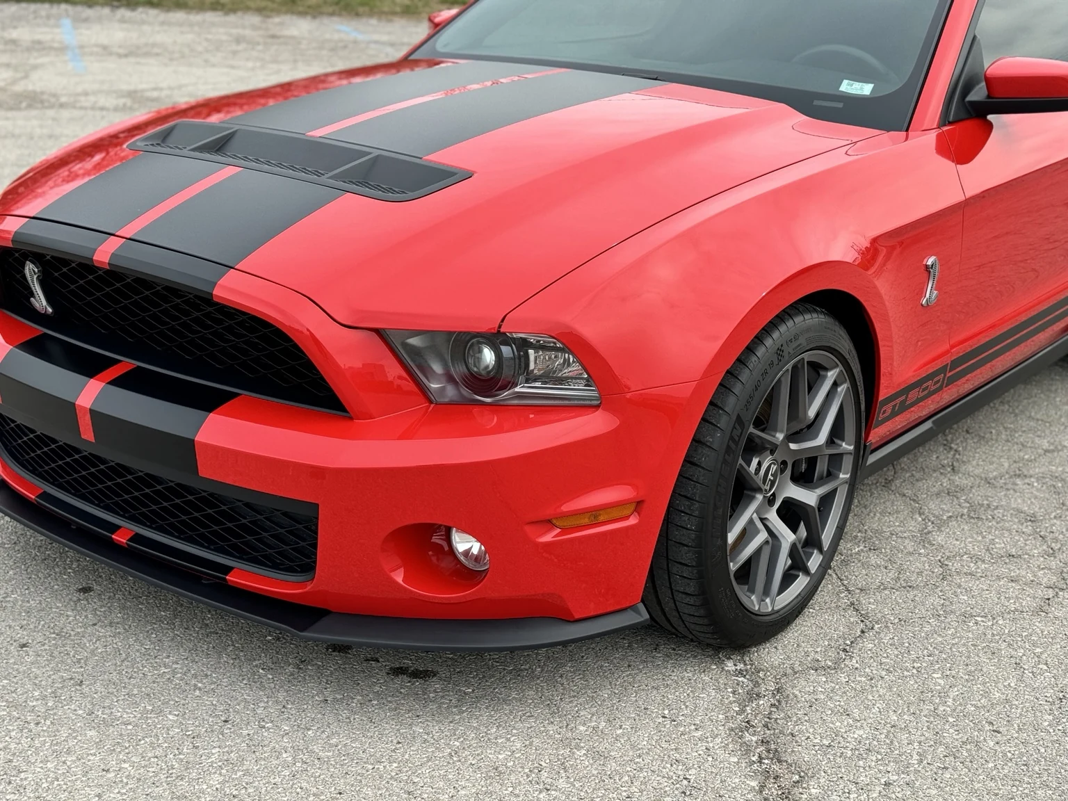 Finished red 2007 Shelby GT500 front end with its black hood stripes and Cobra fender emblem