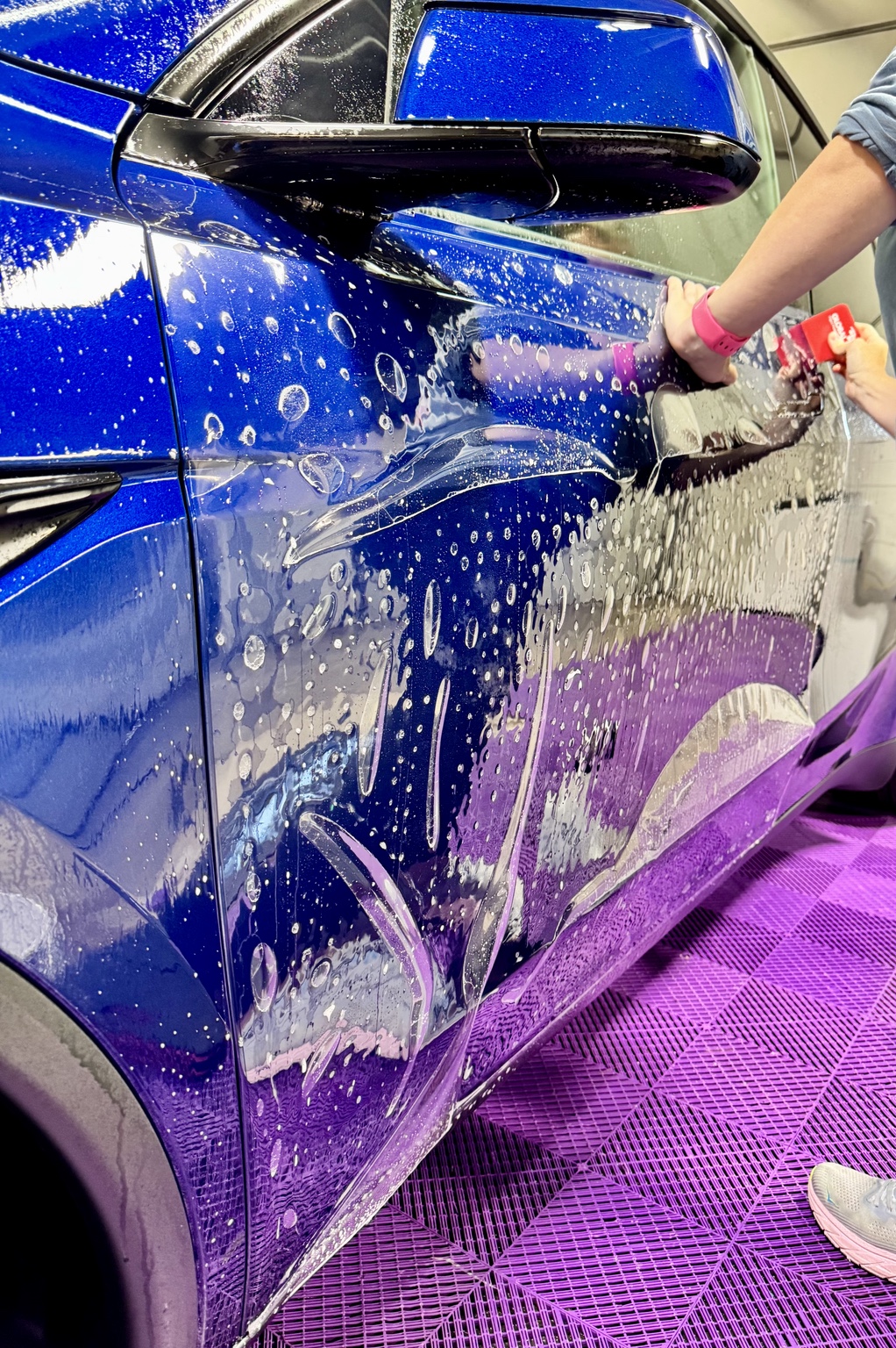 Paint protection film installation on a blue performance car