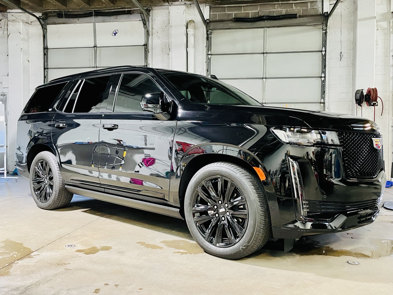 Black Cadillac SUV inside an automotive installation shop
