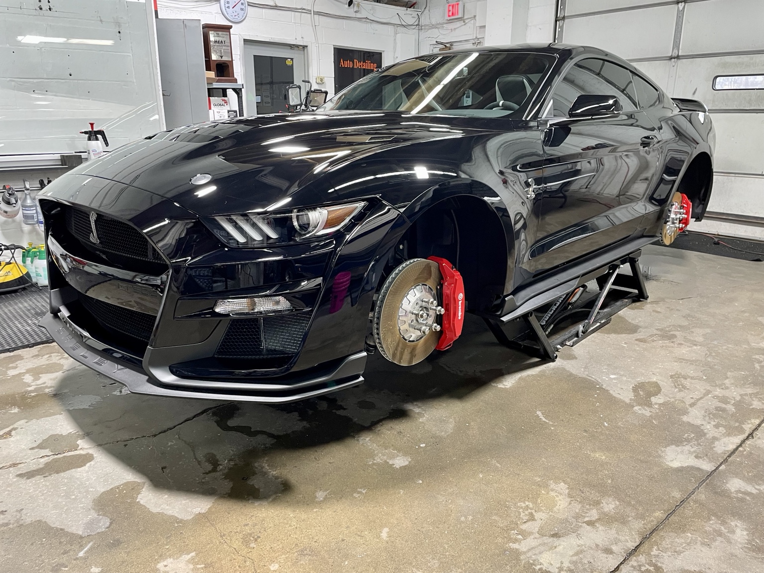 Black Mustang on a lift with wheels removed and red brake calipers visible