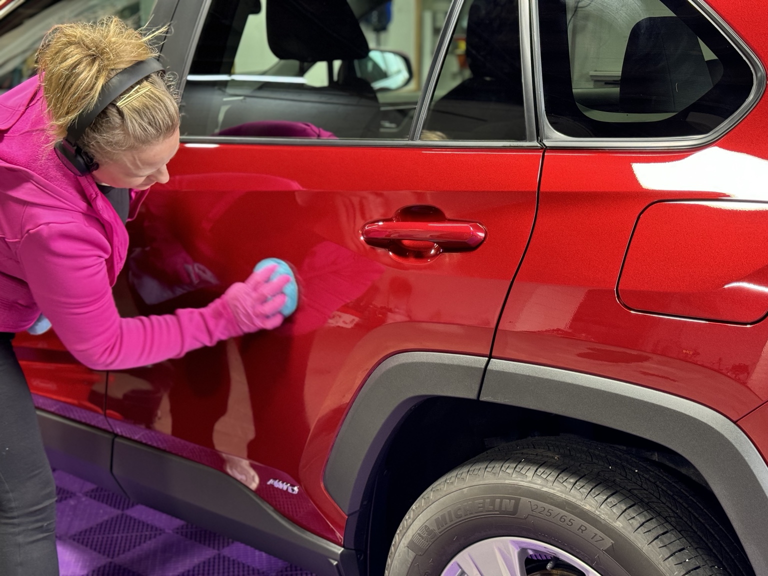 Paint surface preparation on the side of a red SUV inside the shop